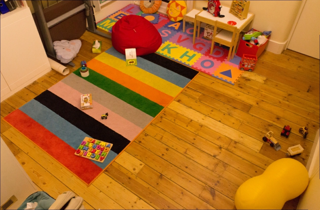 Playroom 中的彩色地毯、玩具与木地板的原始照片
